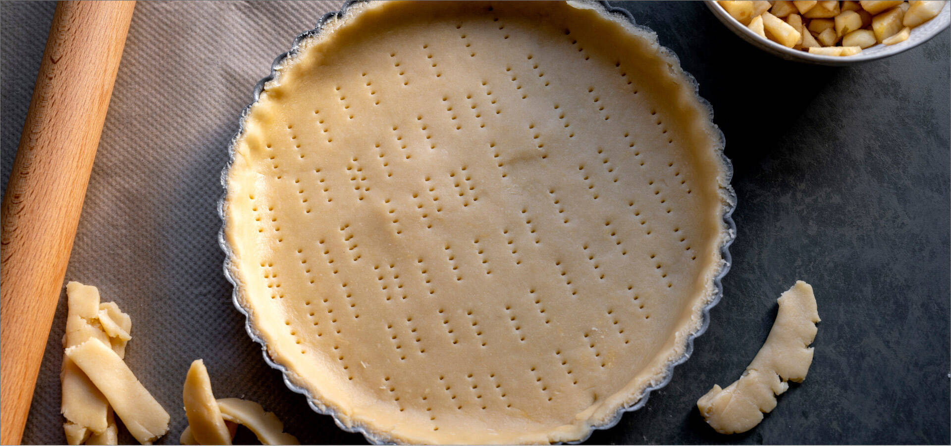 Une pâte à tarte piquetée dans un moule prête à être cuite