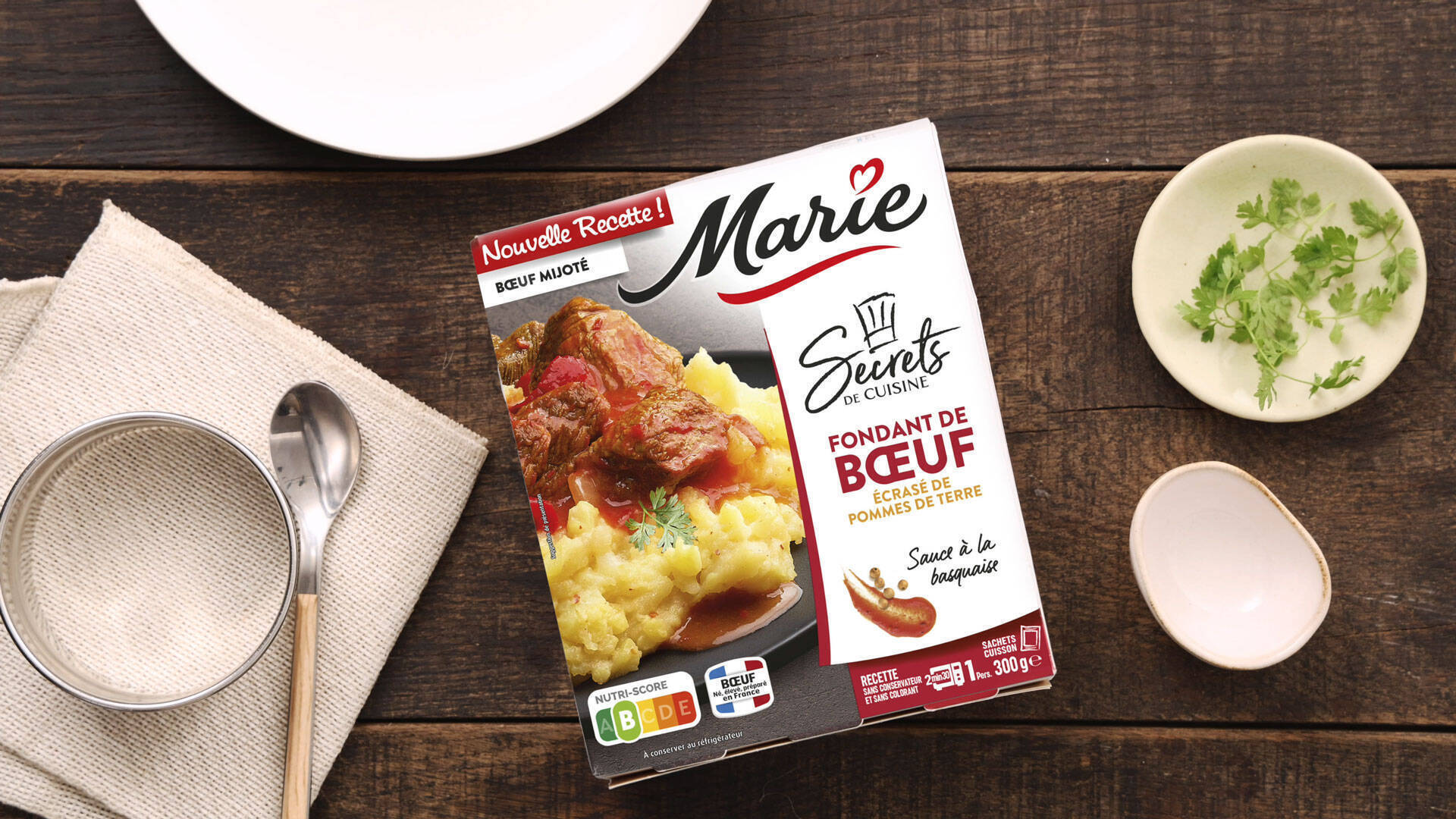 Une barquette de fondant de boeuf sur une table en bois avec une assiette et des accessoires